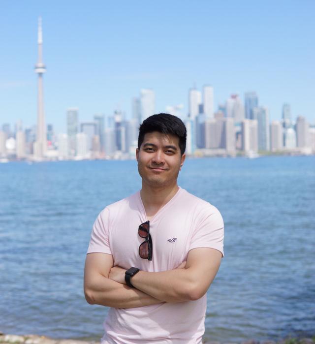 Portrait shot of Philip standing cross-armed in front of the Toronto skyline